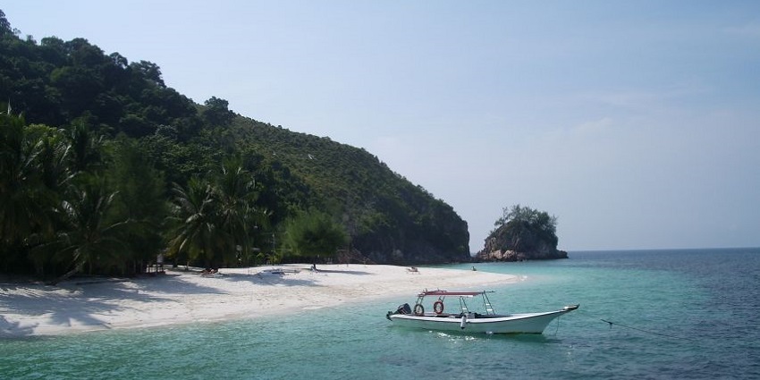 A mesmerising view of a boat on the beach of Rawa Island with azure waters and greenery.