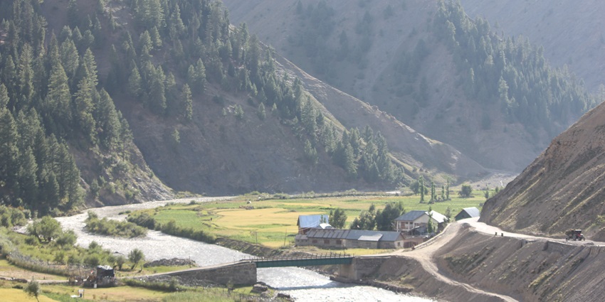 A stunning view of Gurez Valley with a stream flowing through lush green mountains.