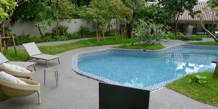 A picture of a resort in Kerala with a swimming pool and greenery all around