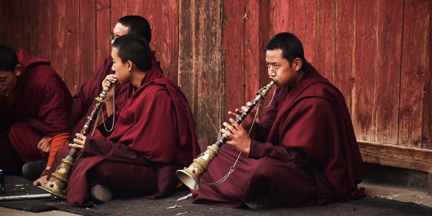 Monks sitting on a mat and playing a musical instrument
