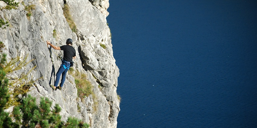 A view of a person climbing on a rock during the day, one of the best things in Kerala.
