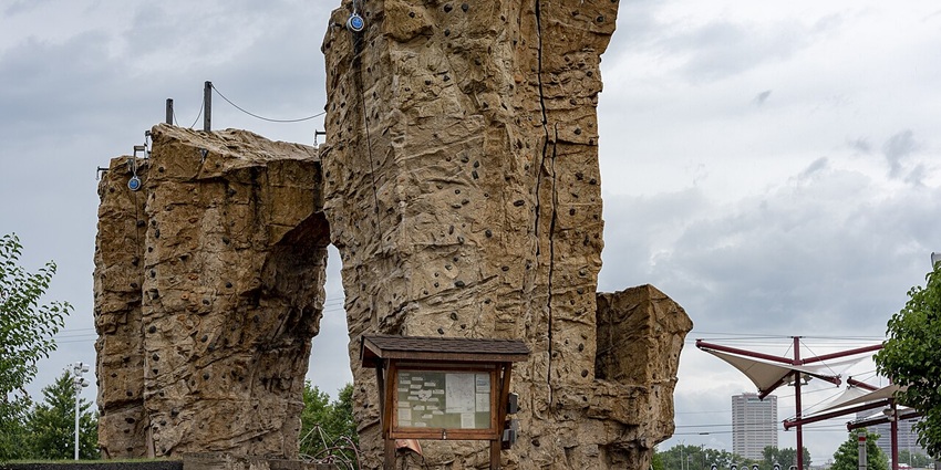 Tall wooden climbing tower with suspended ropes and platforms under bright sky