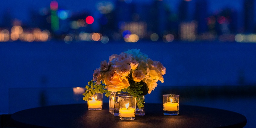 A breathtaking view of a bouquet of flowers on a table with three tea light candles.