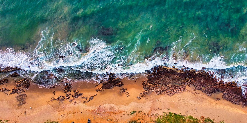 A jaw-dropping aerial view of Rushikonda Beach with waves striking the rocks ashore