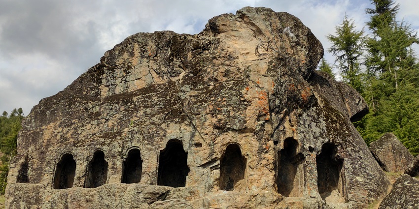 A picture of the entrance of a majestic cave system in Jammu, surrounded by hills