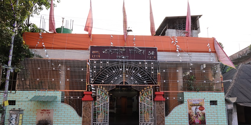 A frontal view of a temple in Munnar with decorated walls and numerous flags waving on its roof