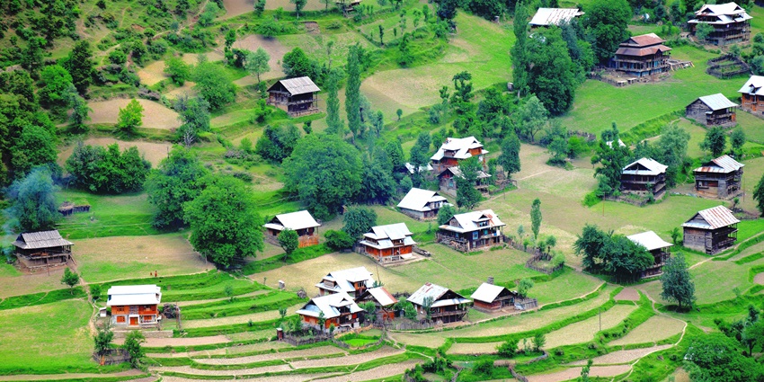 A mesmerising view of a valley in Kashmir with a lot of huts and lush greenery.