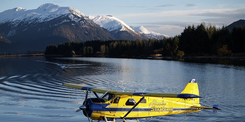 View of a seaplane with a scenic backdrop of snow-capped mountains and pine trees