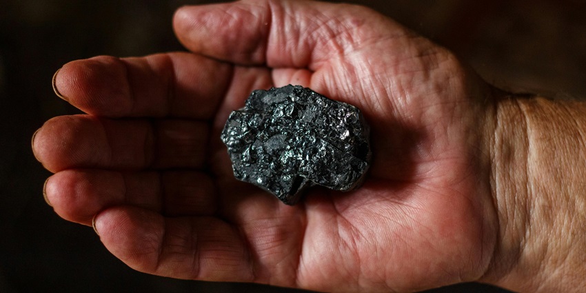 Image of a hand palm holding a black and grey coal - visit the underground coal mining replica