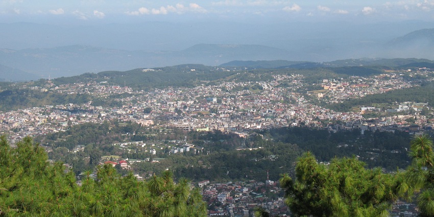 A panoramic view of Shillong, nestled among lush green hills under a clear blue sky