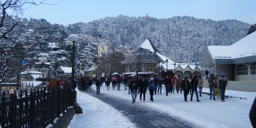 People walking on a road with snow-covered mountains in background