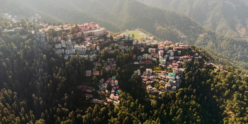 A bird eye view of Shimla, showcasing the city's buildings nestled among lush green hills.