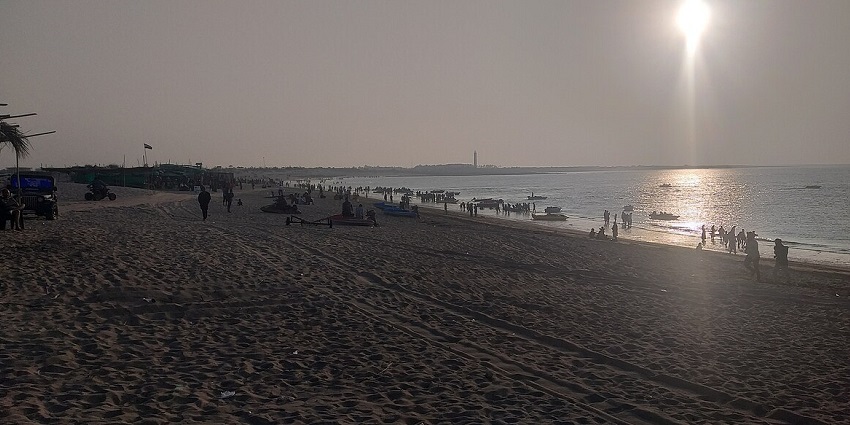 An evening view at Shivrajpur Beach in Gujarat with people strolling along the coastline