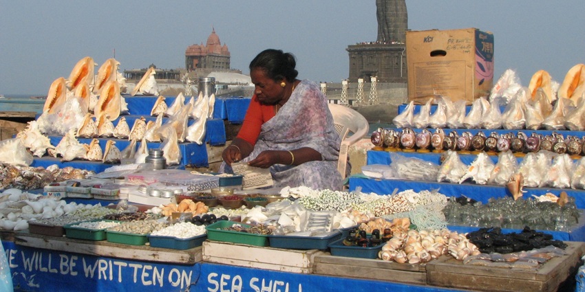 Woman selling shells that can be customised with your name for a unique shopping experience