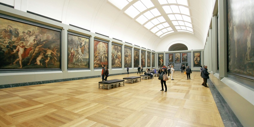 Exhibit of framed paintings on display in an art gallery with soft lighting.