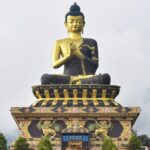 A view of a large statue of lord Budhha in Sikkim on top of a lush green mountain.