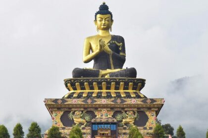 A view of a large statue of lord Budhha in Sikkim on top of a lush green mountain.