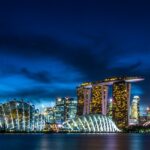 A breathtaking night view of Singapore covered in bright lights with an ocean on the side.