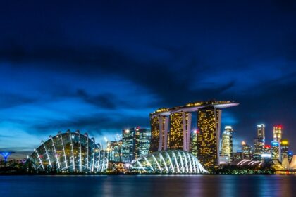 A breathtaking night view of Singapore covered in bright lights with an ocean on the side.