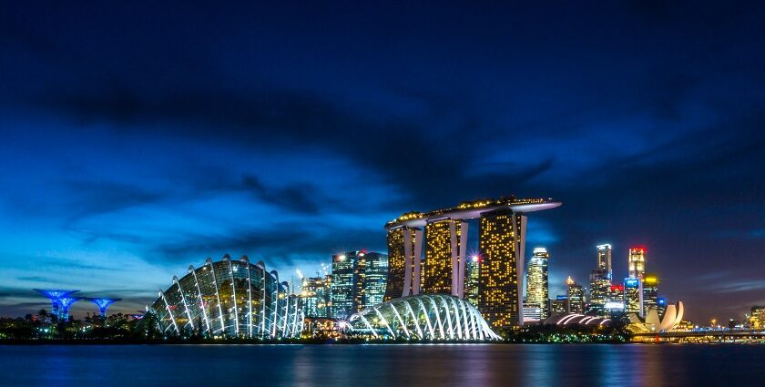 A breathtaking night view of Singapore covered in bright lights with an ocean on the side.