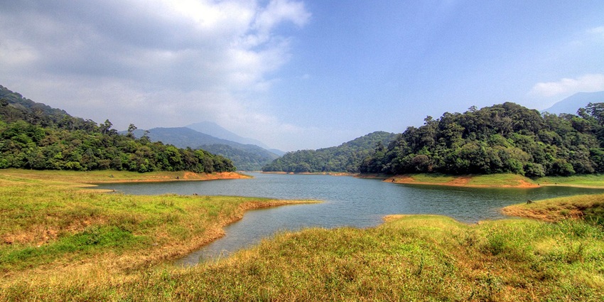 A picture of a scenic water body in Attapadi, surrounded by lush greenery and hills