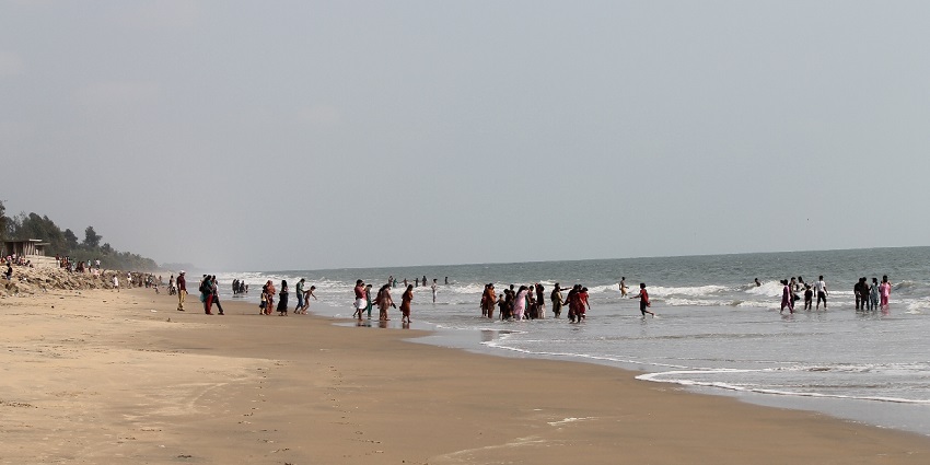 Tourist watching the waves crash at the sandy shores of the Snehatheeram Beach