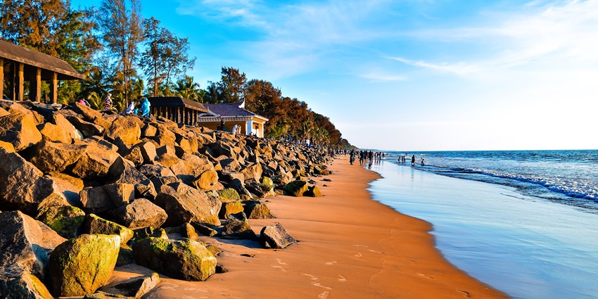 Golden sandy shoreline with calm waves and palm trees at Snehatheeram Beach–beaches near thrissur