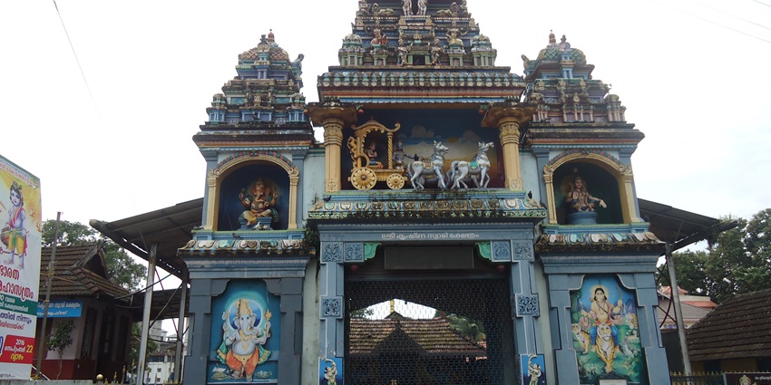 A frontal view of a traditional Hindu temple with a tall gopurama and carved deities