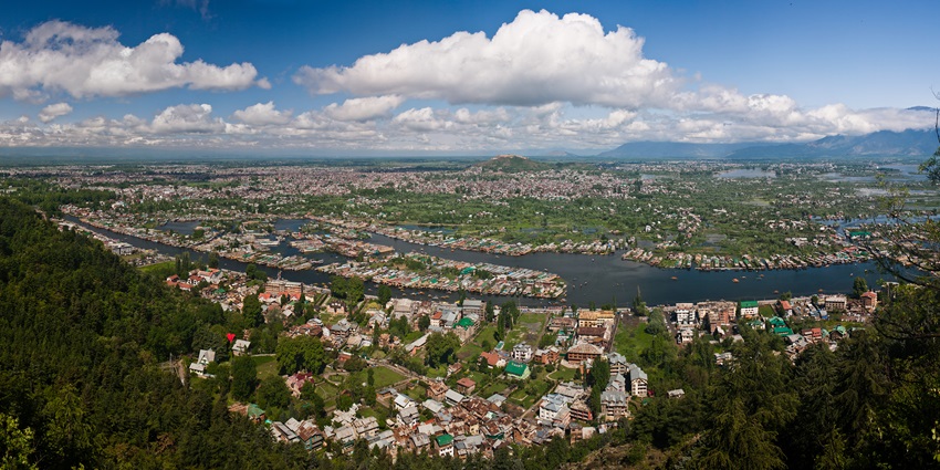 A panoramic aerial view of a township with a lake in the middle and greenery all around