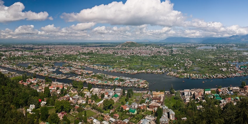 A panoramic view of a hill station with a cover of greenery and a lake in the centre