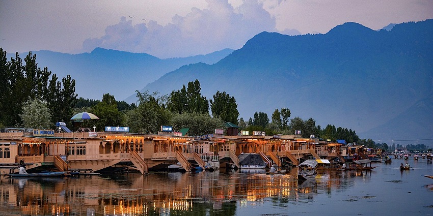 A beautiful view of the houseboats in Srinagar. There are green trees in the background.