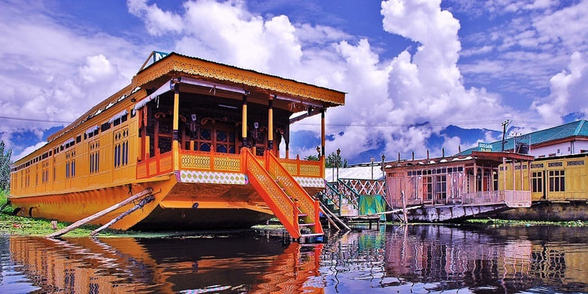 Traditional wooden houseboat on Dal Lake, Srinagar, surrounded by snow-capped mountains