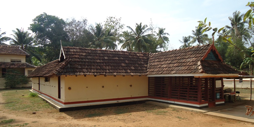 A sideways picture of a traditional Hindu temple in Munnar with tall pine trees in the background
