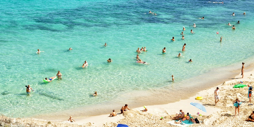 The view of sunbathers relaxing on a sandy beach, with turquoise waters and playing