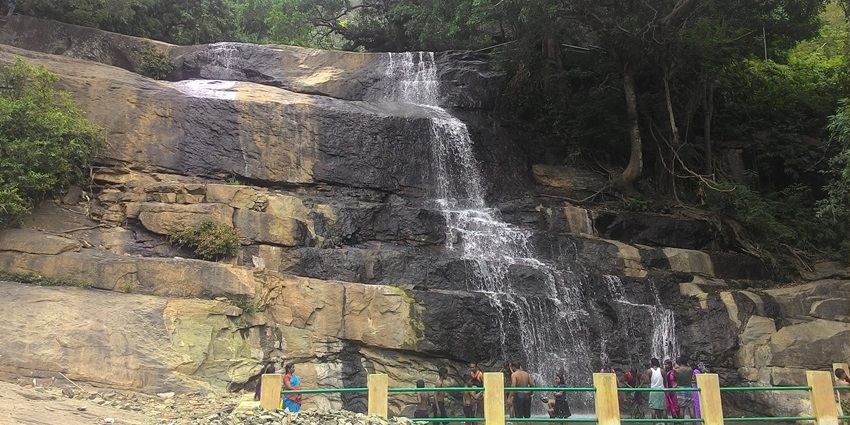 Glistening Chinna Suruli Falls cascades into a lush gorge under clear skies in Tamil Nadu