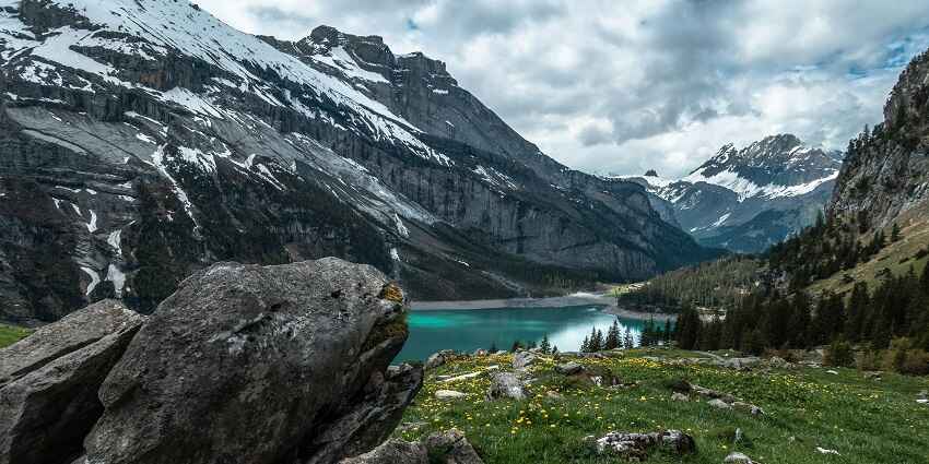 A scenic view of the Oeschinen Lake in Switzerland with snow-clad peaks in background