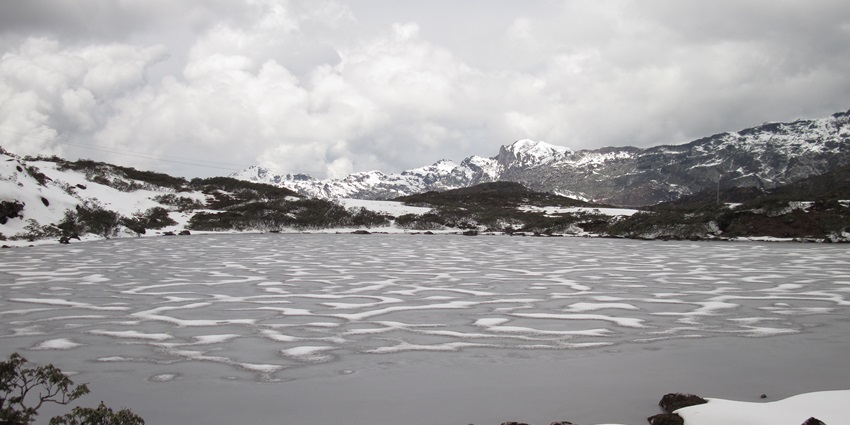 Enchanting winter view of Tawang with snow-covered surrounding mountains and lake.