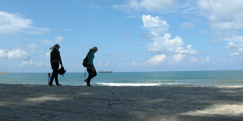 he view of two person walking at Teluk Kampi, one of the Penang Beaches, Malaysia.