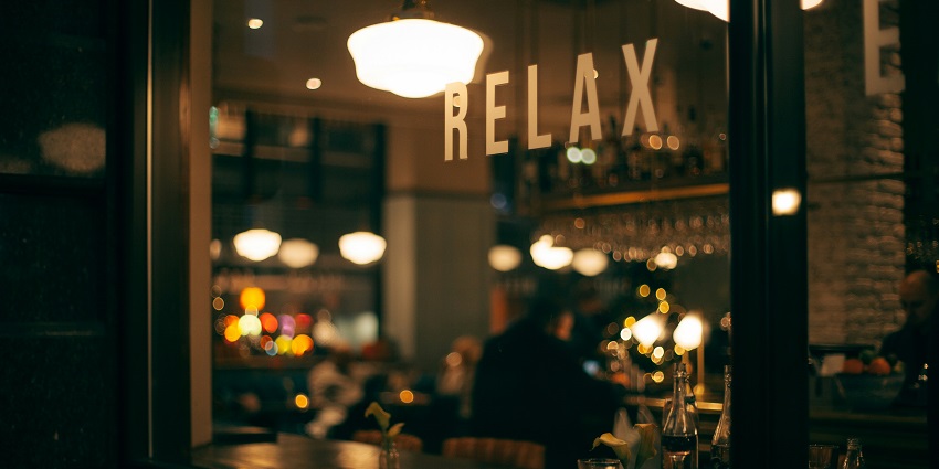 A view of a restaurant with yellow lights and a signboard saying relax in bold letters.