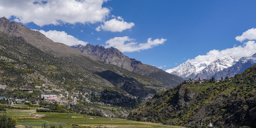 A serene panoramic view of a town and fields in Himachal Pradesh, India.