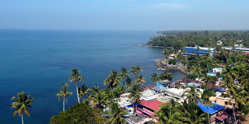 An enchanting view of Thangassery Lighthouse with turquoise waters and greenery around it.
