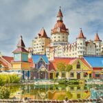 A stunning view of colourful buildings near a water body in a theme park during the day.