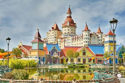 A stunning view of colourful buildings near a water body in a theme park during the day.