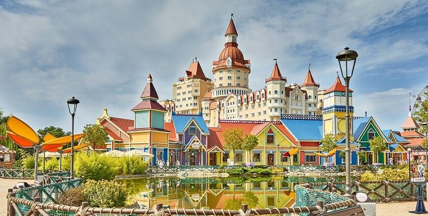 A stunning view of colourful buildings near a water body in a theme park during the day.