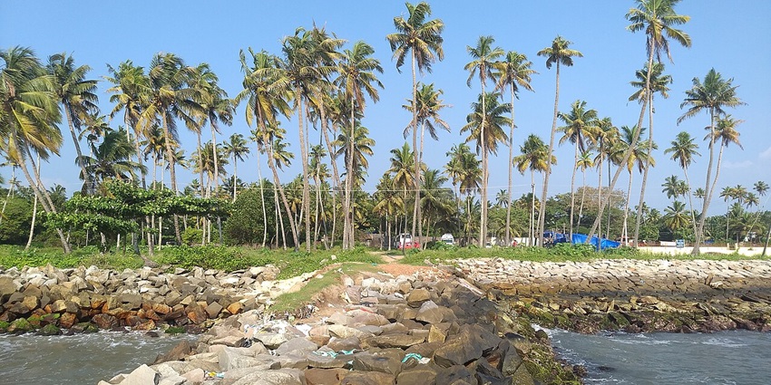 A view of Thirumullavaram Beach with gentle waves and golden sand, near Kumbhavurutty waterfalls.