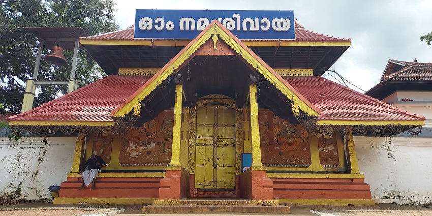 A frontal view of the Thirunakkara Mahadeva Temple with a red roof and yellow walls.