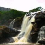 Scenic view of descending Thoovanam Waterfall amidst the lush greenery and hills