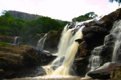 Scenic view of descending Thoovanam Waterfall amidst the lush greenery and hills