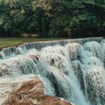 A mesmerising view of Trivandrum waterfalls flowing through rocks around lush greenery.