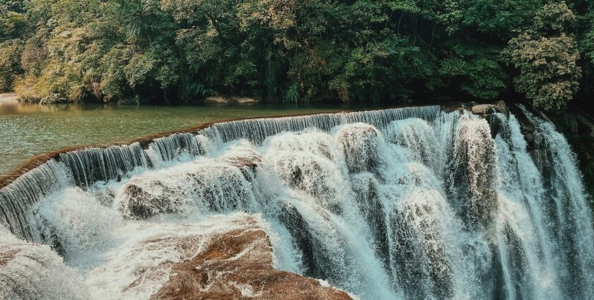 A mesmerising view of Trivandrum waterfalls flowing through rocks around lush greenery.